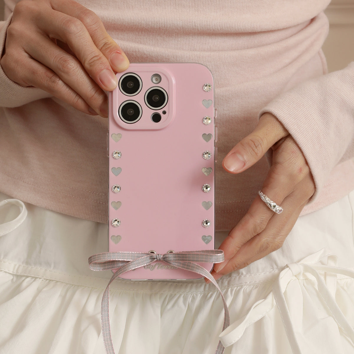 Person holding a pink phone case with heart designs 
