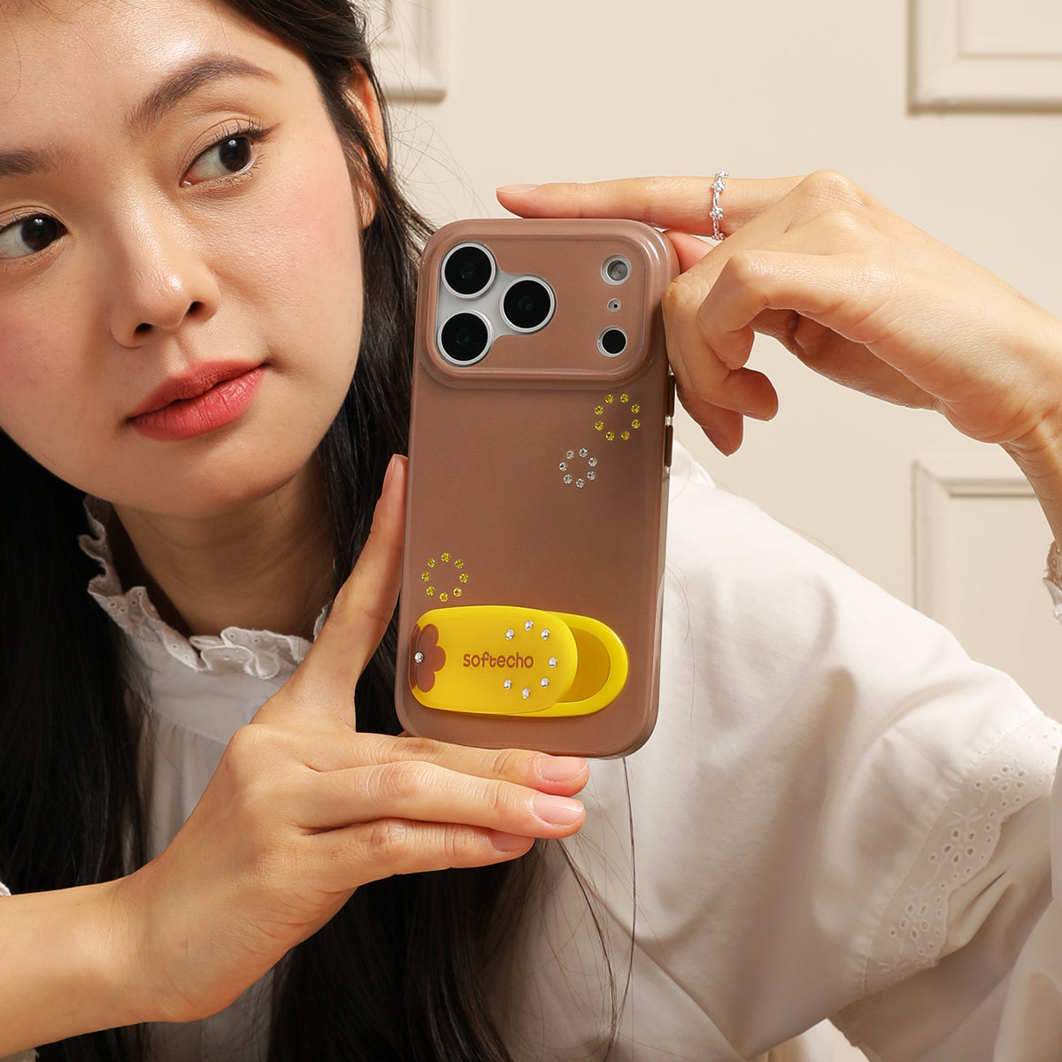Person holding a phone case with a design on a neutral background