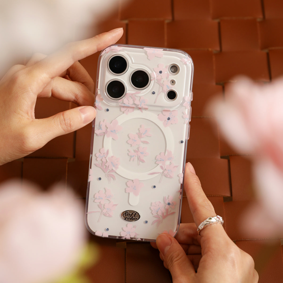 Phone case with floral design held by hands on a blurred background