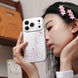 Woman holding a phone with a star-patterned case, wearing pink hair clips.
