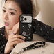 Woman holding a black phone case with floral designs and 'Softecho' branding.