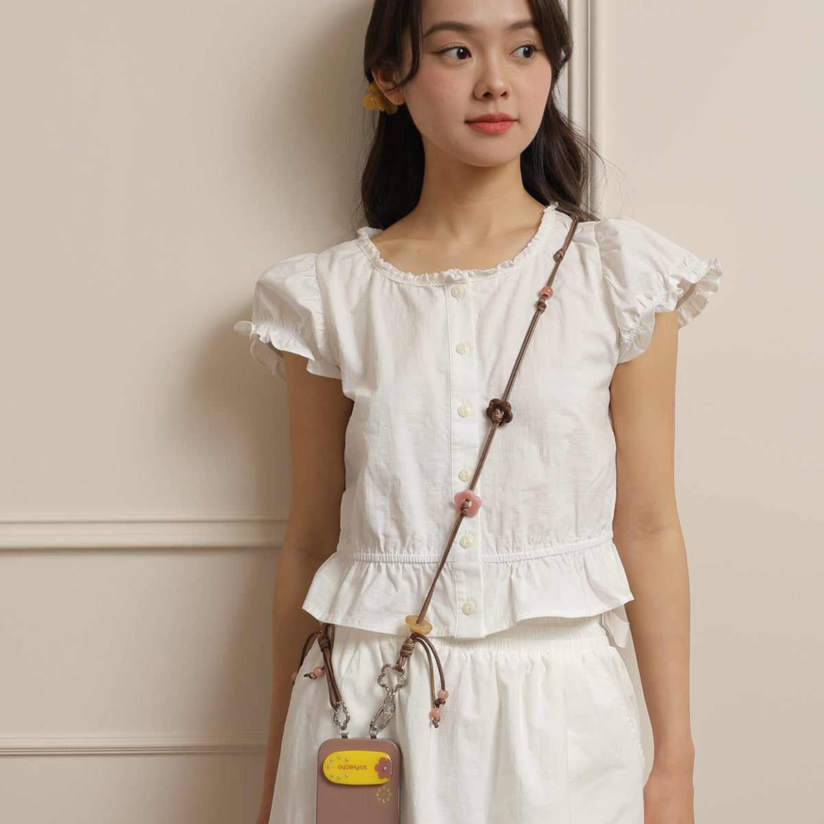 Woman wearing a white blouse holding a small brown bag with a strap.