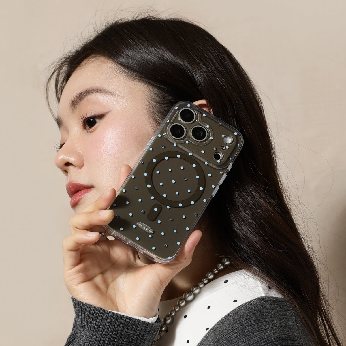 Woman holding a phone case with polka dots and a pop socket against a beige background