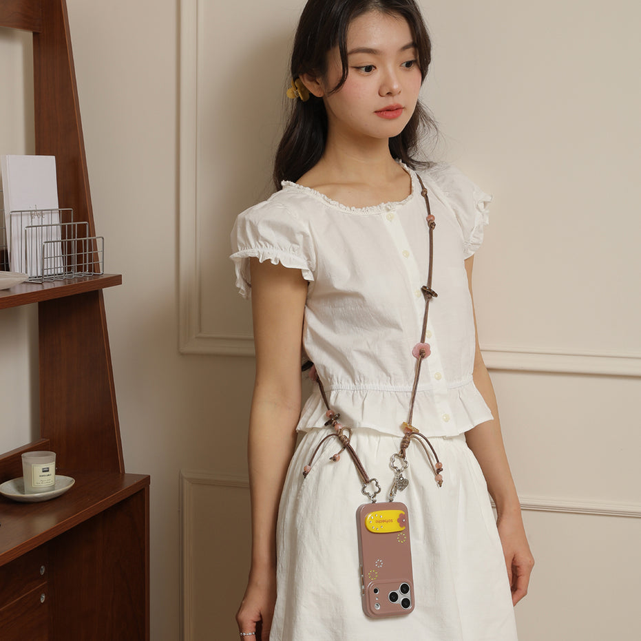 Woman wearing a white dress with a phone case hanging from her strap in an indoor setting.