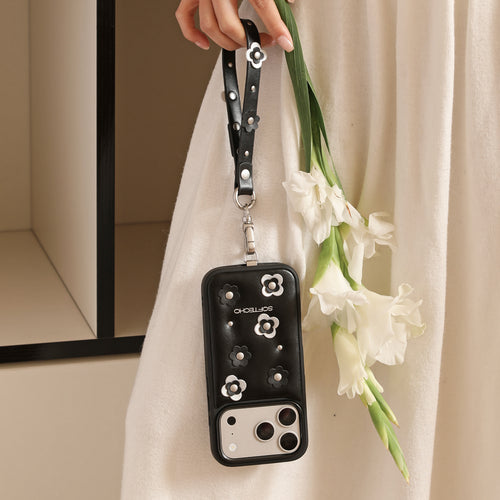 Black floral phone case held by a hand with a white flower arrangement against a neutral background