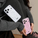 Two phone cases, one white and one pink, held by a person wearing a gray sweater.
