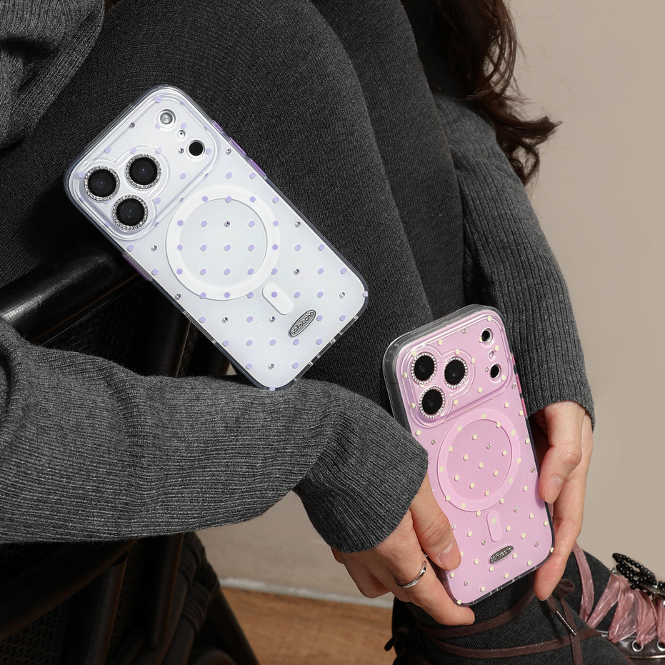 Two phone cases, one white and one pink, held by a person wearing a gray sweater.