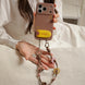 Person holding a phone with a decorative strap, wearing a white lace top.