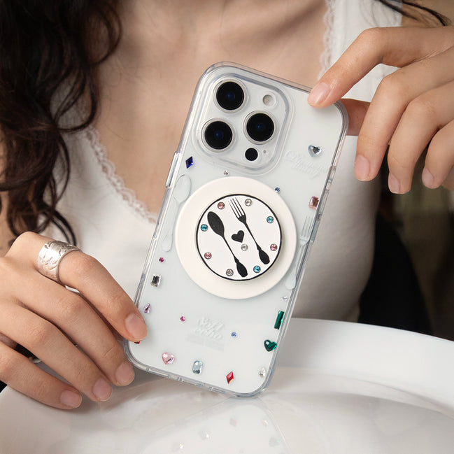Person holding a phone with a clear case featuring a spoon, fork, and heart design.
