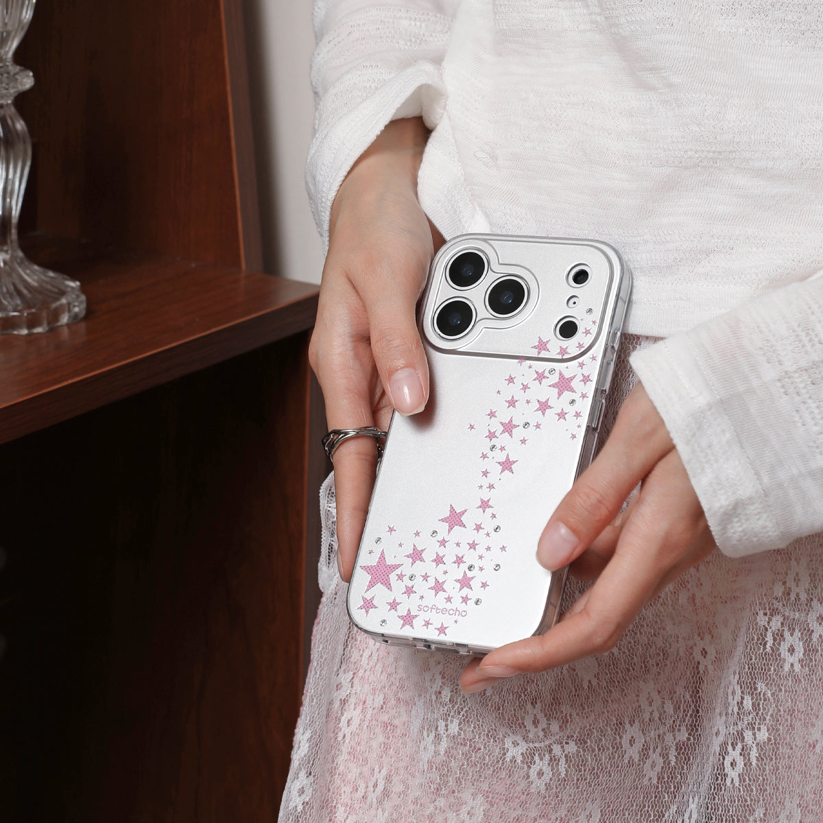 Person holding a phone with a star-patterned case in a neutral setting