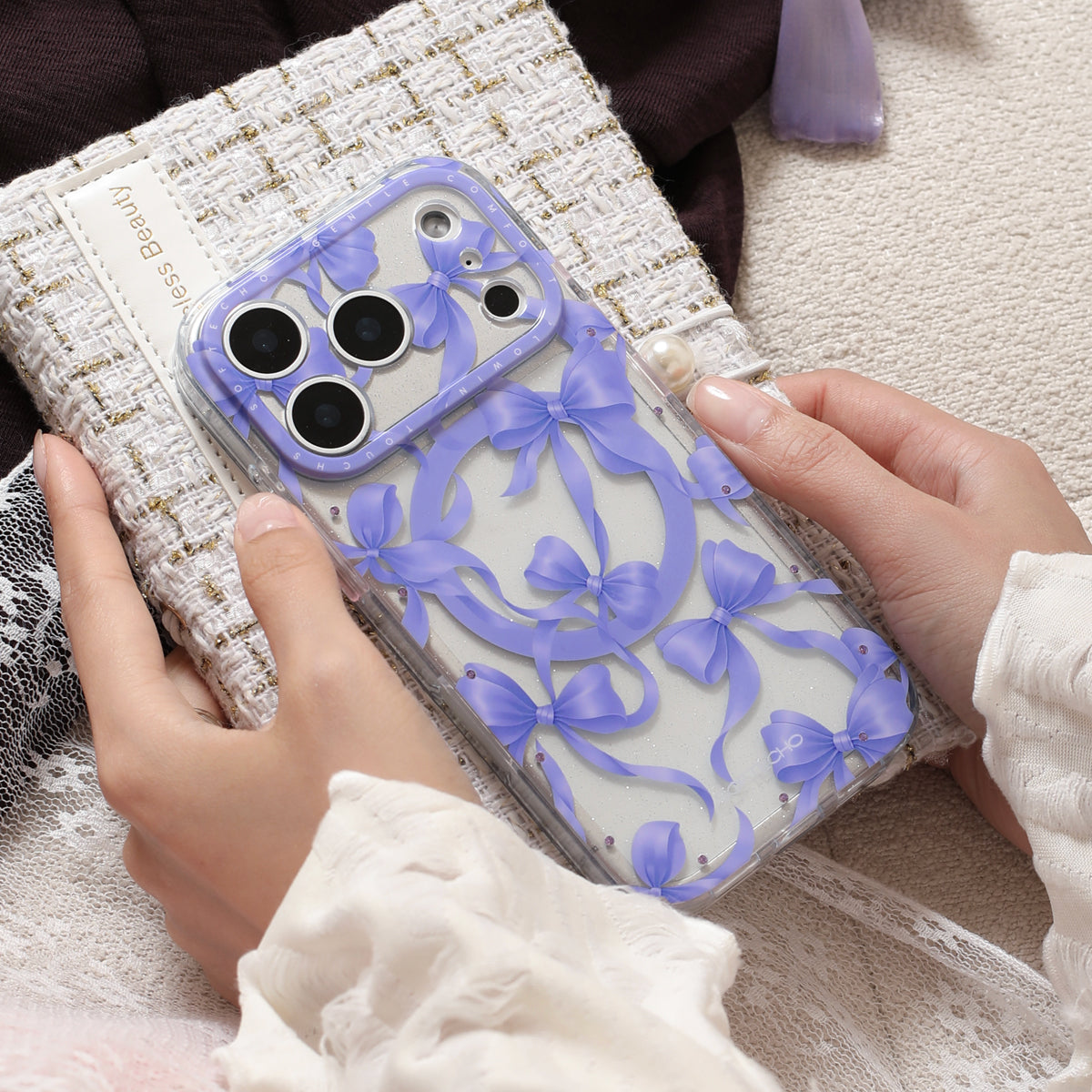 Phone case with blue ribbons held by hands on a textured surface