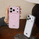 Person holding a pink phone case with a white case on a wooden surface