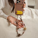 Person holding a phone with a decorative case and charm