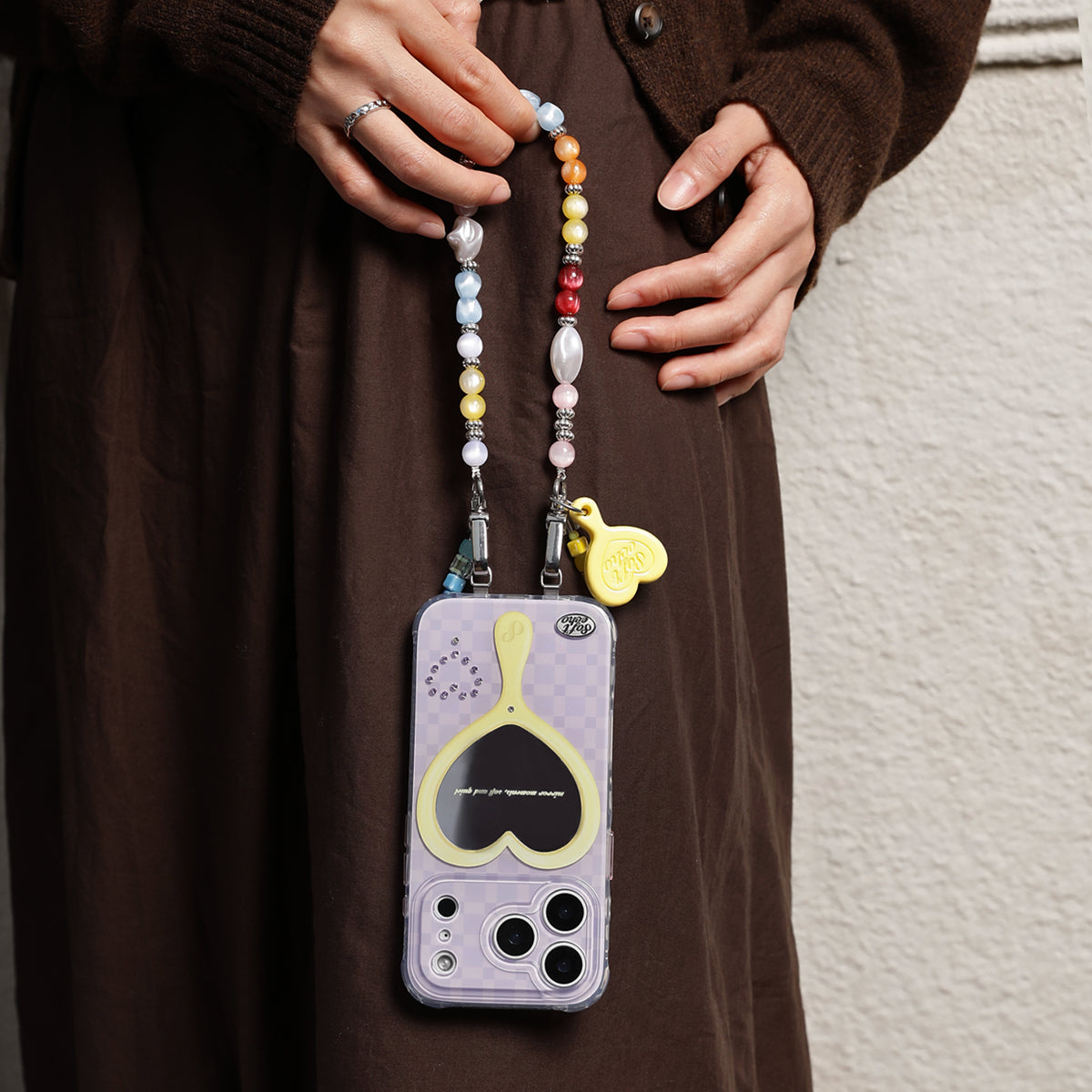 Person holding a phone case with a colorful beaded strap 