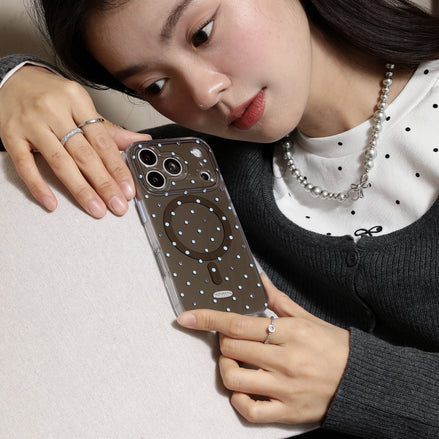 Woman holding a phone with a clear case featuring circular designs.