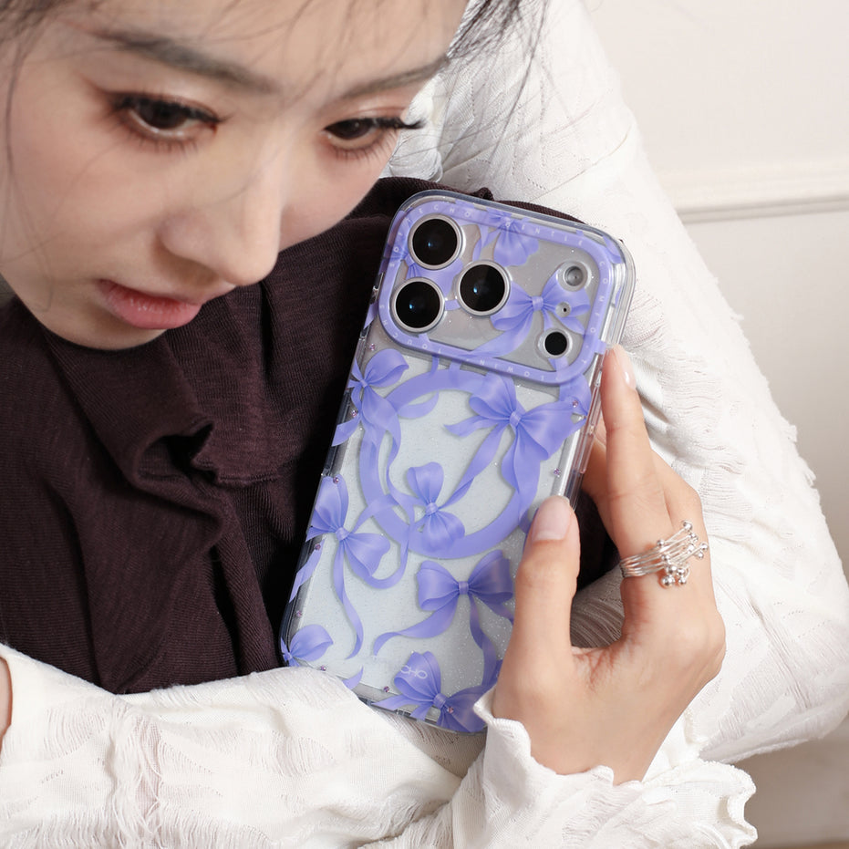 Person holding a phone with a floral case, wearing a white coat and brown sweater.