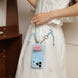 Person holding a blue phone case with a lanyard, wearing a white outfit.