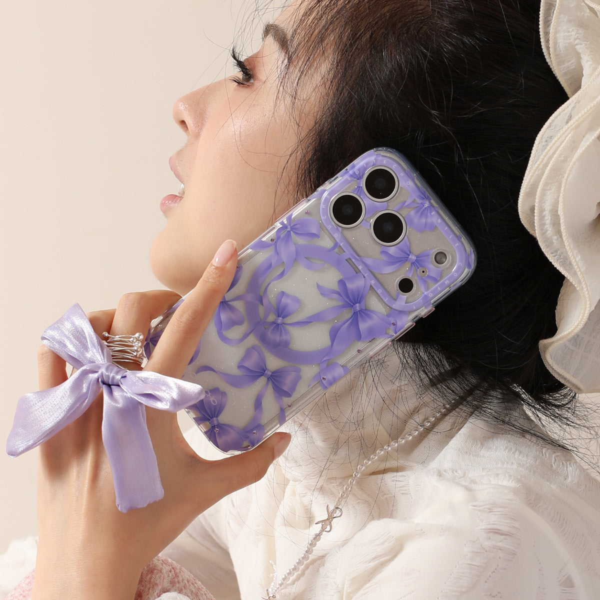 Person holding a phone with a purple bow case against a neutral background