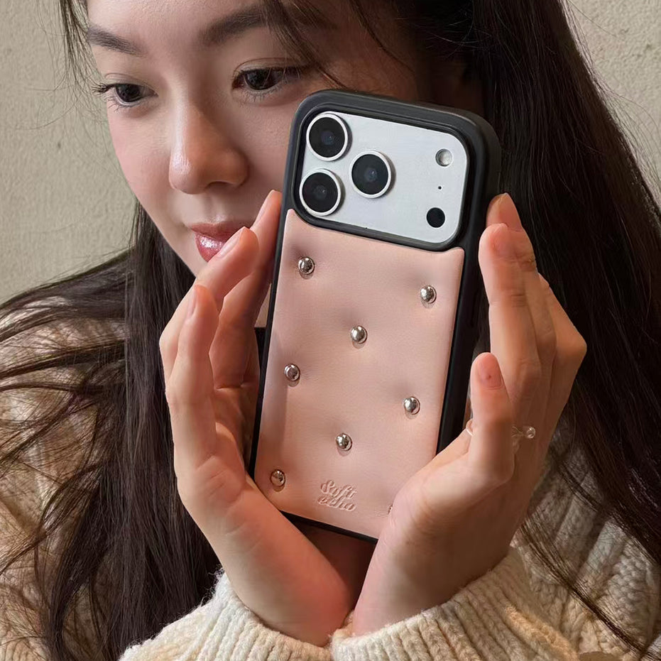 Person holding a phone with a decorative case featuring silver studs.