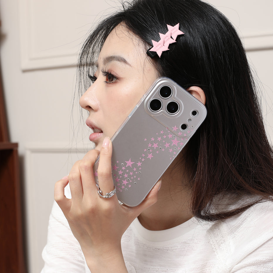 Person holding a phone with a star-patterned case against a neutral background