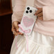 Person holding a phone with a heart design and pink ribbon, wearing a light pink sweater.