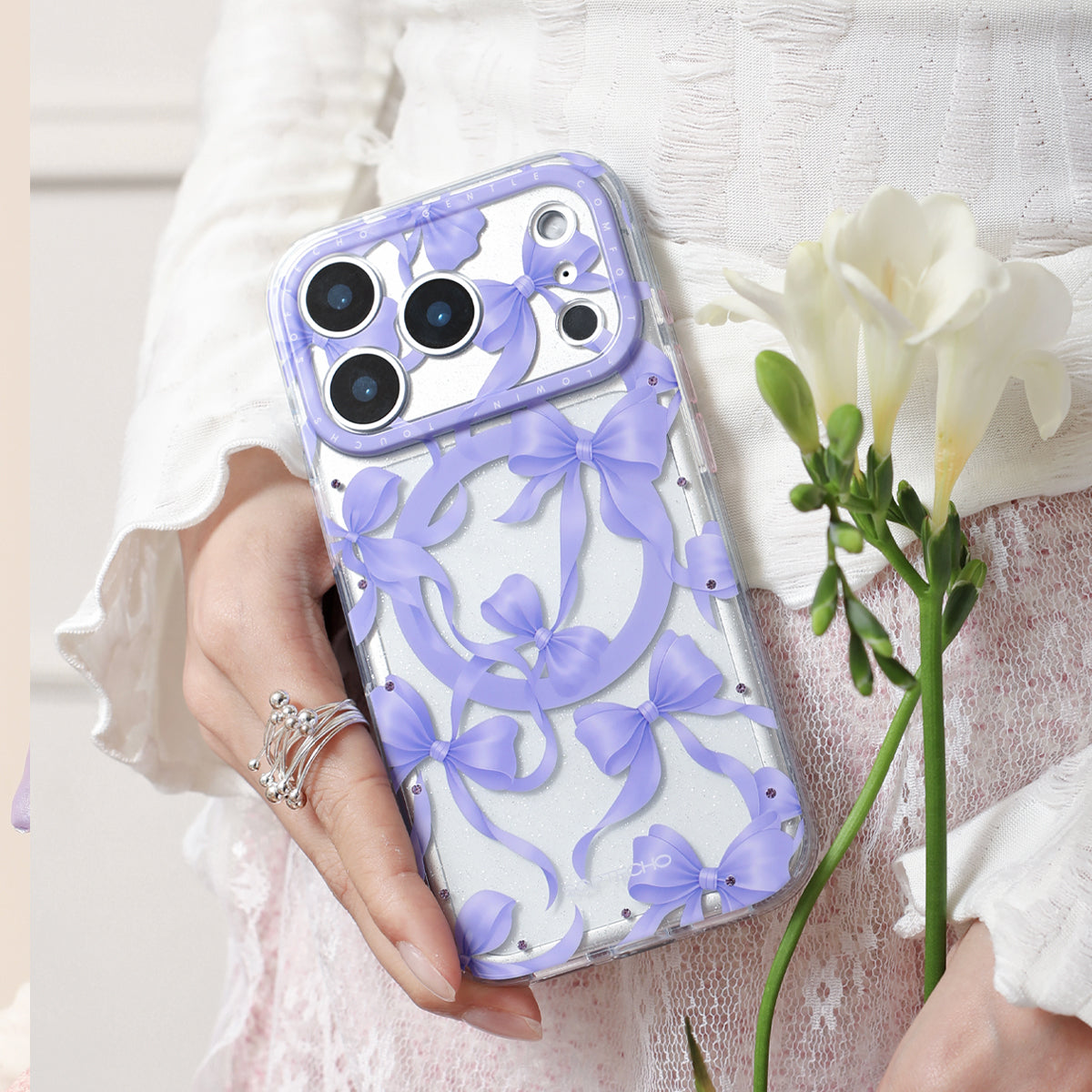 Phone case with purple bow design held by a person with a white flower.