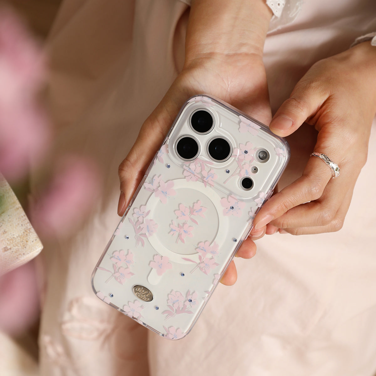 Person holding a phone with a floral case, blurred background