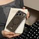 Person holding a phone with a polka dot case on a stack of books