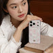 Woman holding a phone with a floral case on a wooden surface