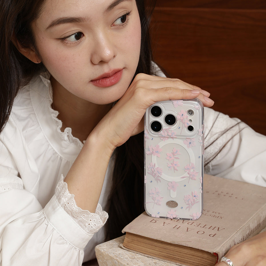Woman holding a phone with a floral case on a wooden surface