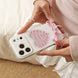 Person holding a phone case with a decorative heart design and pink bow.