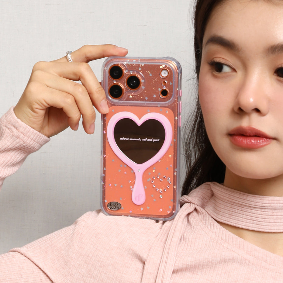 Person holding a phone case with a heart mirror 