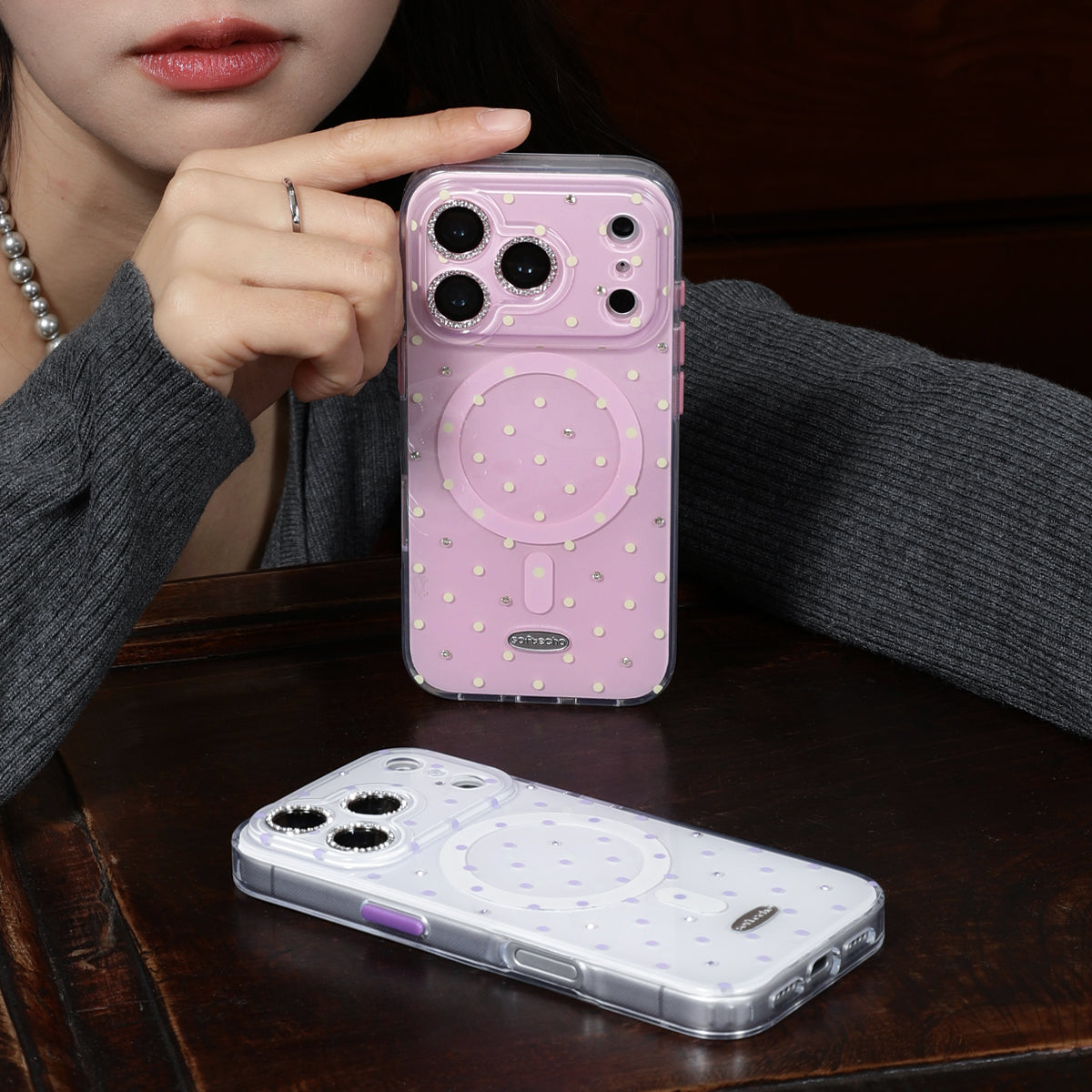 Person holding a pink phone case with a clear bottom half on a wooden surface.
