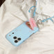 Blue phone case with a pink heart charm and blue lanyard on a white fabric background