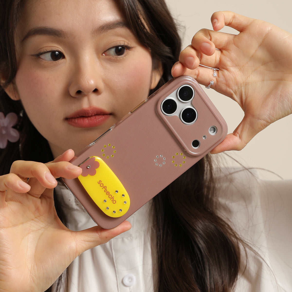 Person holding a phone with a decorative case featuring a cartoon character.