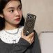 Woman holding a smartphone with a polka dot case against a neutral background