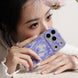Person holding a phone with a floral case, wearing a white blouse.
