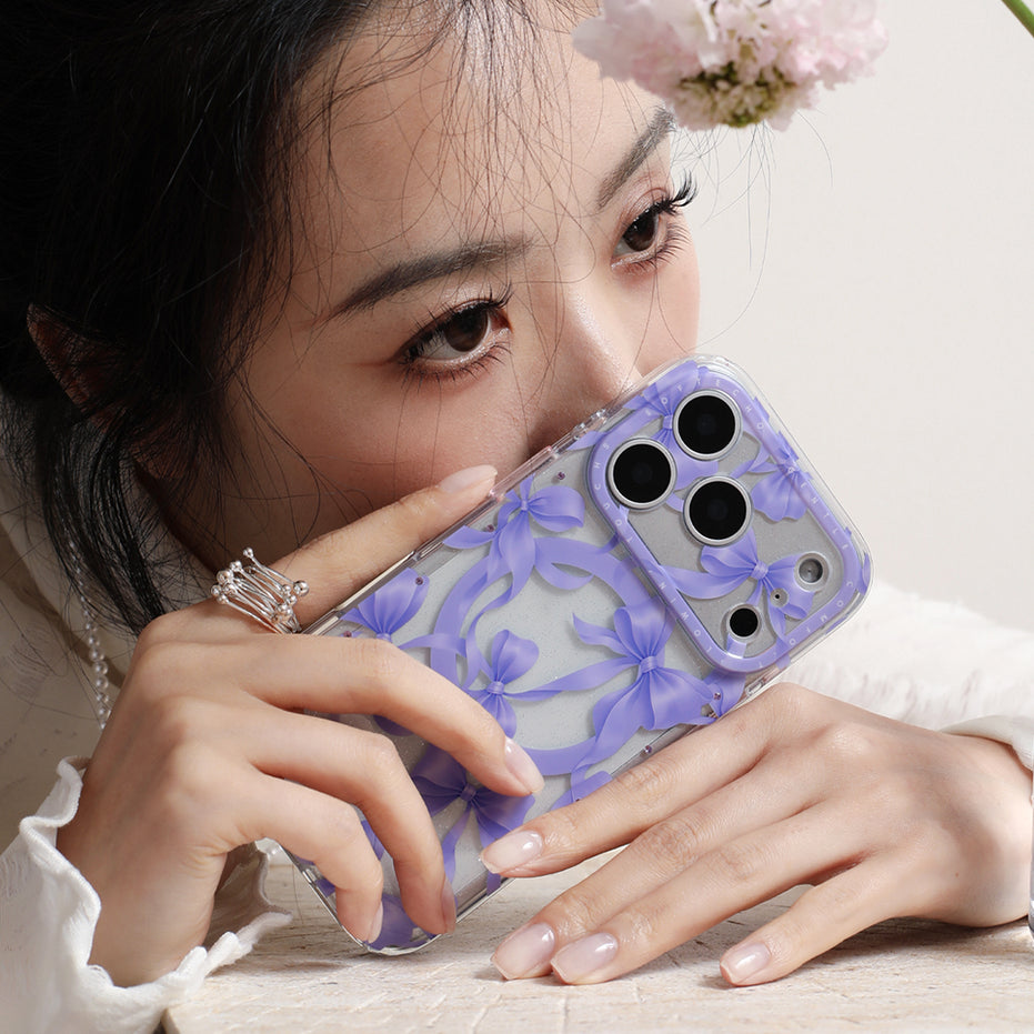 Person holding a phone with a floral case, wearing a white blouse.