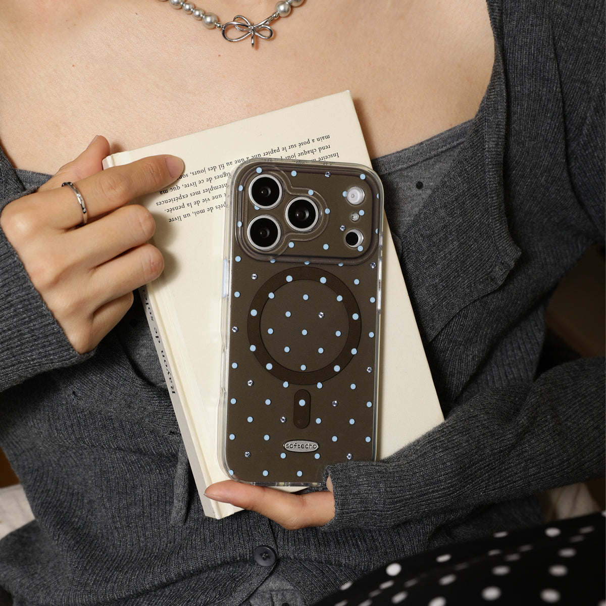 Person holding a phone with a polka dot case over a book