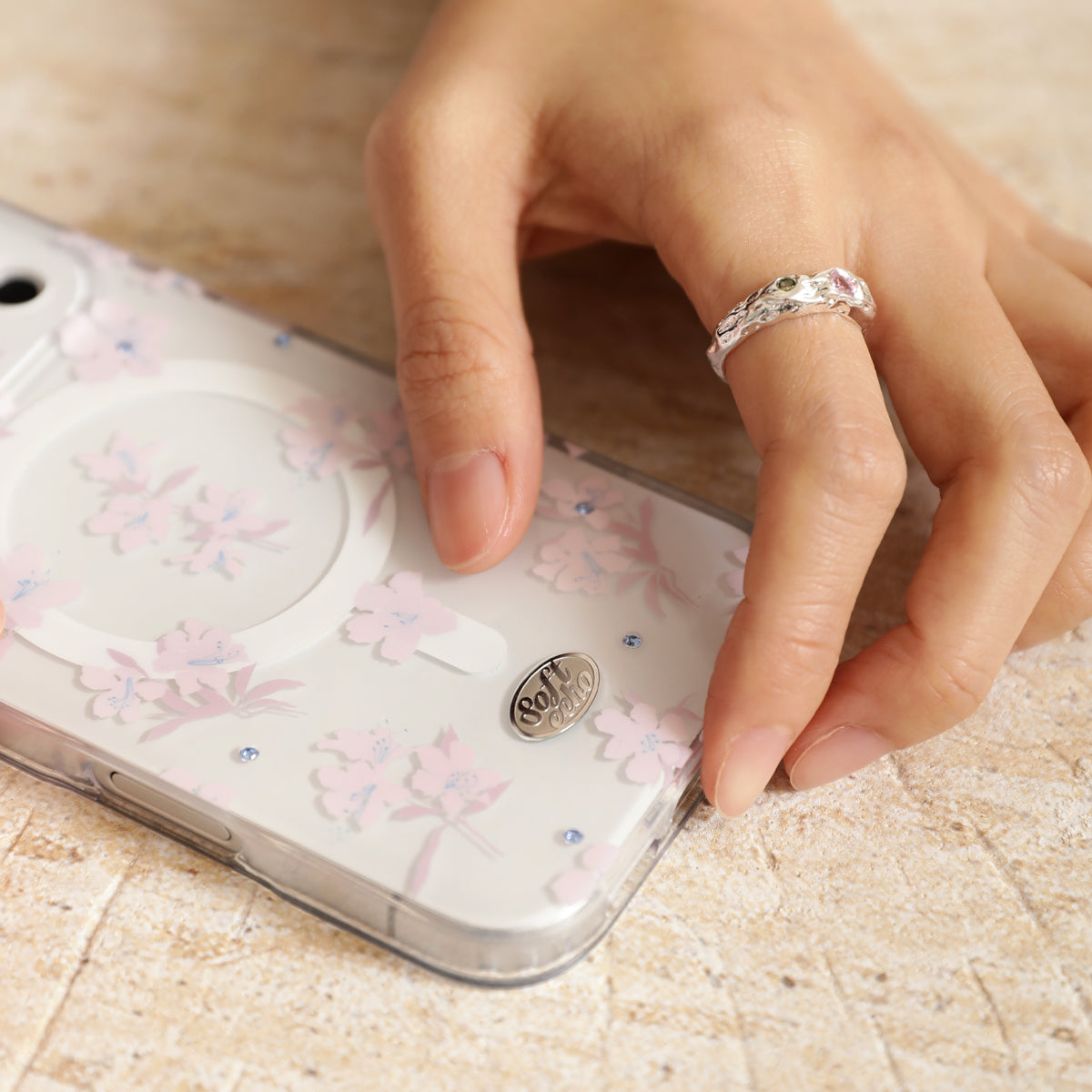 Hand with a ring on a phone case with floral design