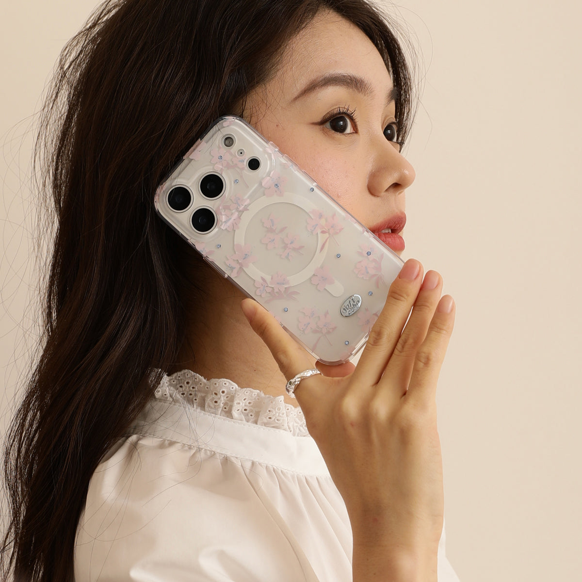 Woman holding a phone with a floral case against a beige background